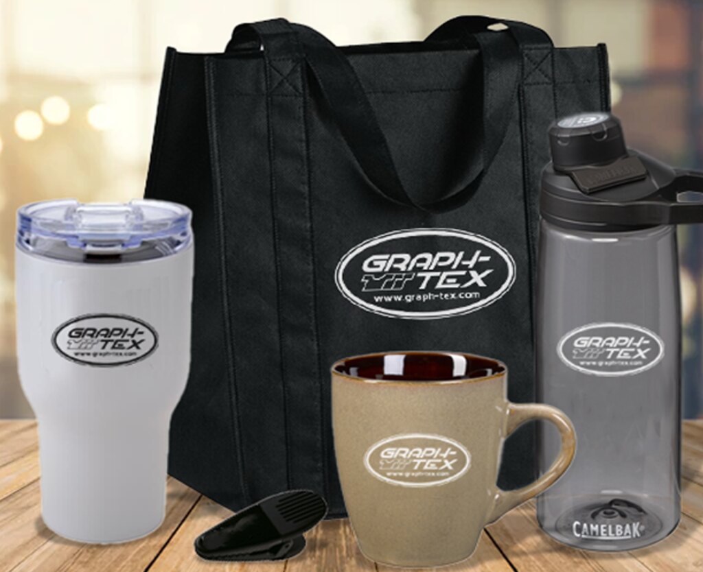 Branded promotional products — Graph-Tex tote bags, travel tumblers, a ceramic mug and a water bottle, each carrying the company oval