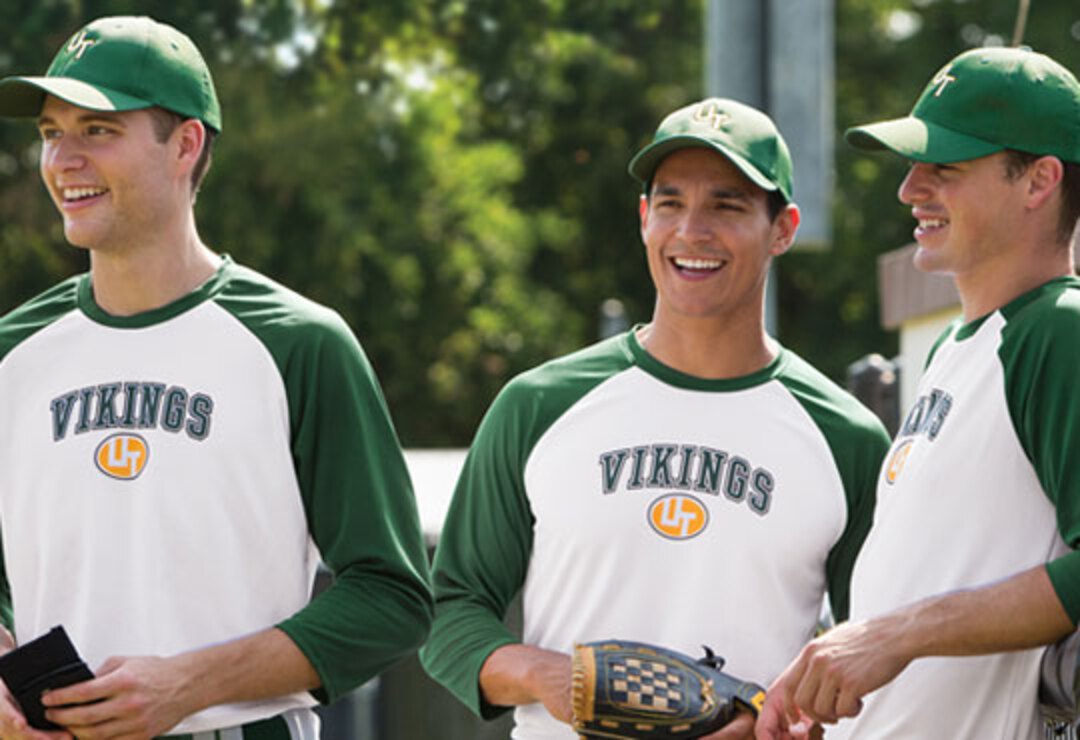 Three baseball players in green and white Vikings raglan jerseys and matching caps